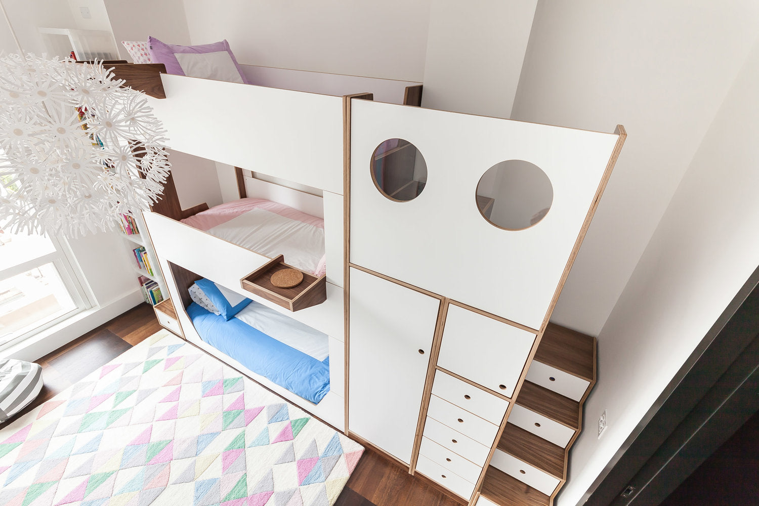 Modern bunk bed with storage, circular windows in a bright, airy children’s room.