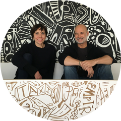 Two people sitting, abstract black and white mural behind.