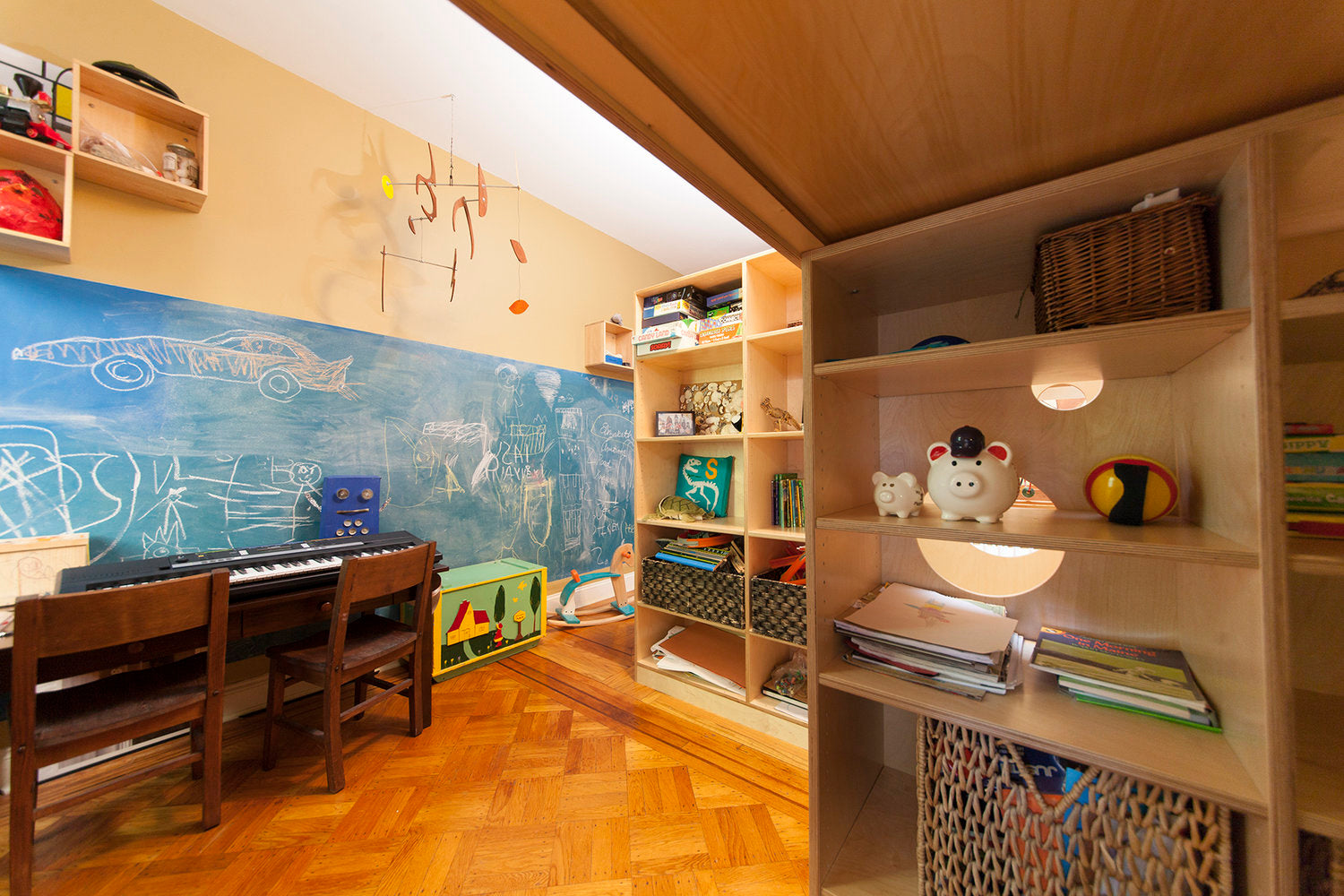 Child’s room with piano, chalkboard wall, shelving, toys, and books.