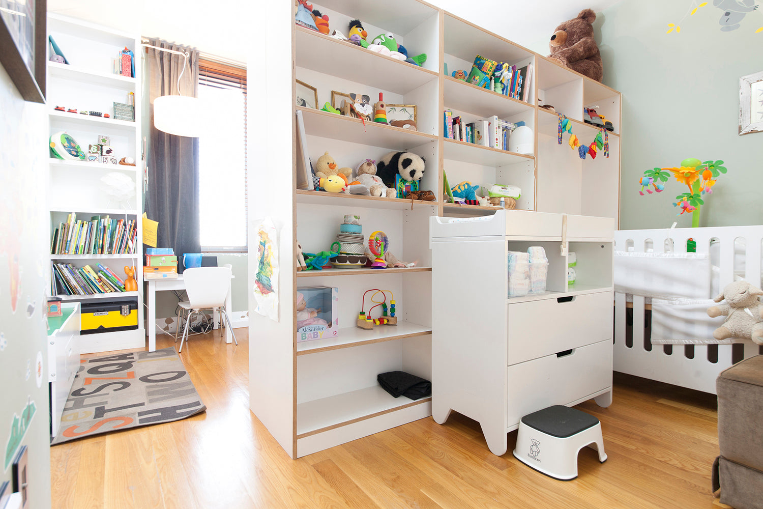 Bright nursery with crib, bookshelf, toys, and colorful decor.