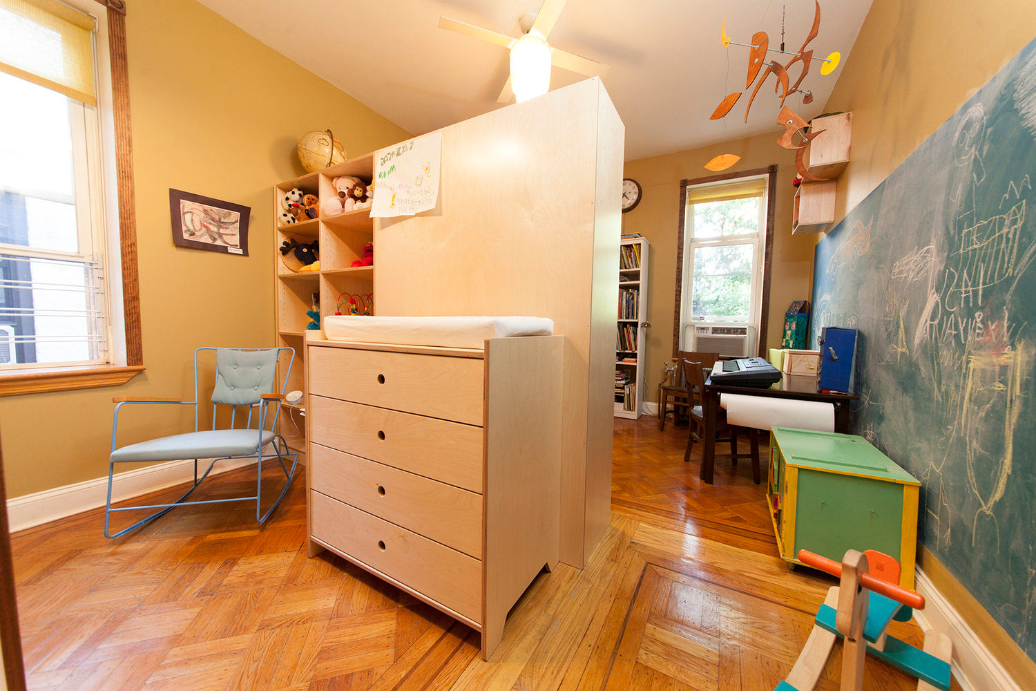 Cozy child’s room with loft bed, study area, and chalkboard wall.