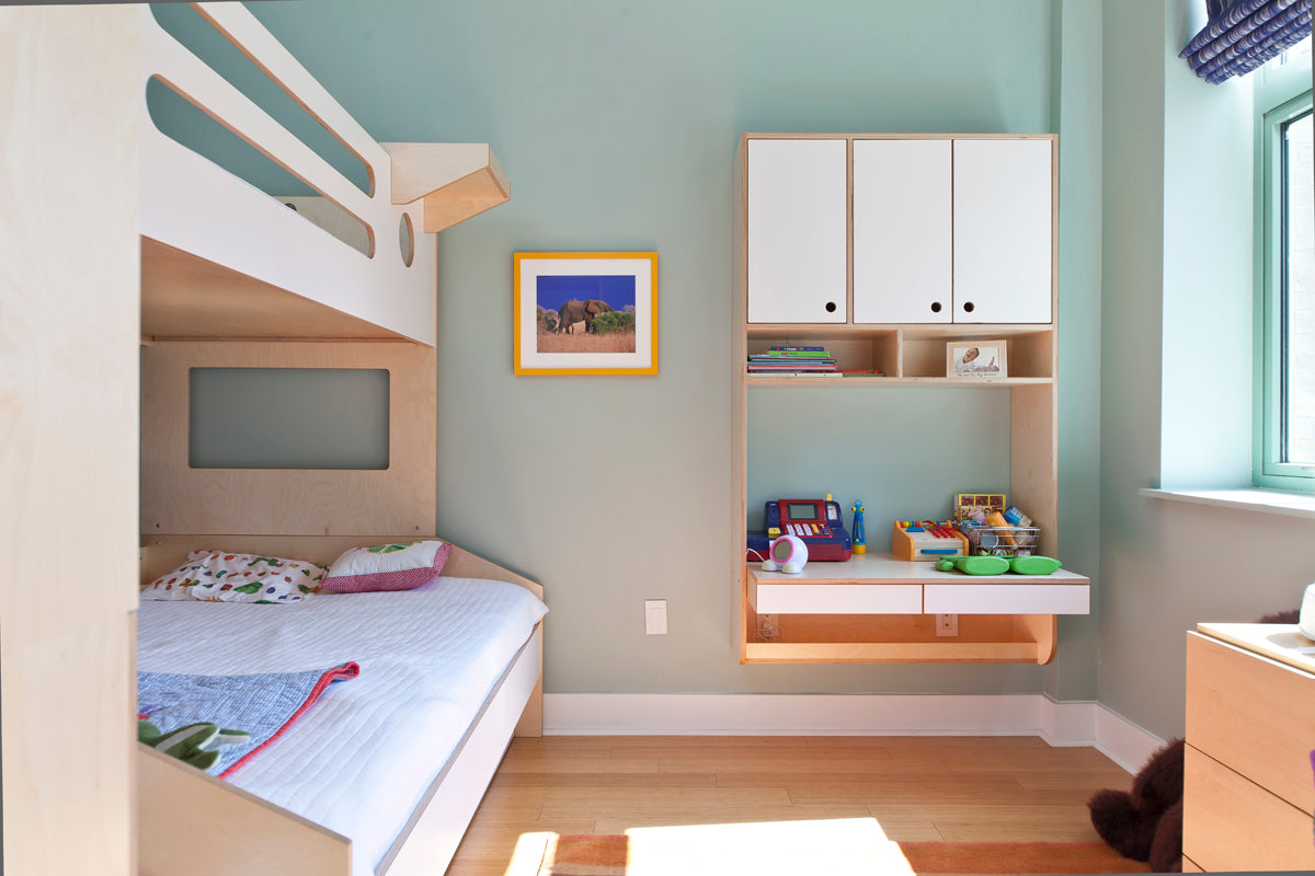 Modern child’s bedroom with bunk bed, cabinets, desk, and toys.