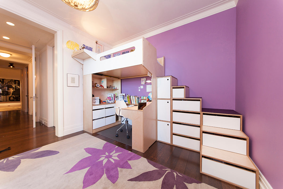 Interior with purple wall, loft bed, desk, and flower rug.