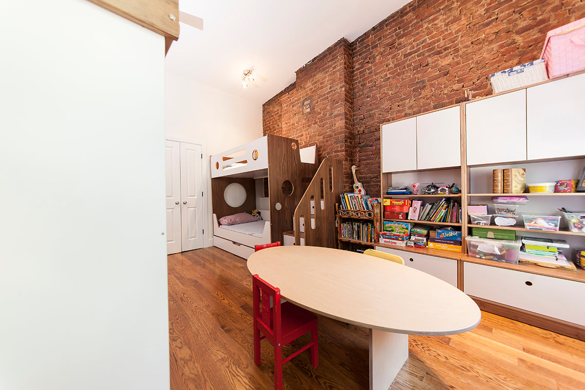 Cozy children’s room with bunk bed, bookshelf, and oval table.