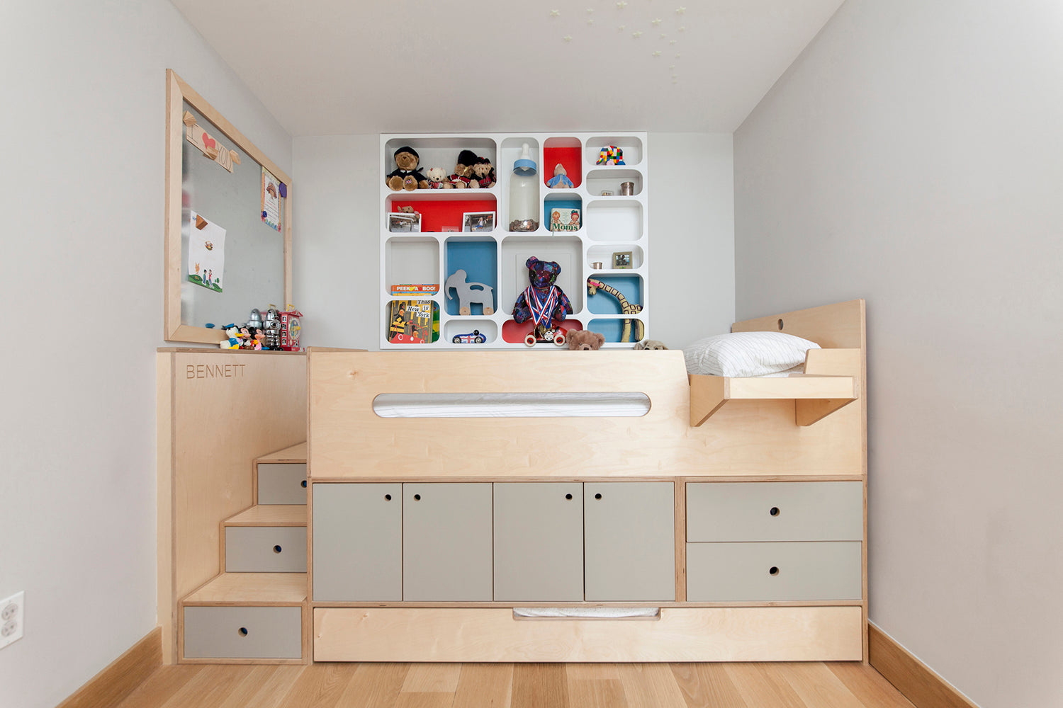 Modern child’s room with built-in bed, storage, colorful toys.