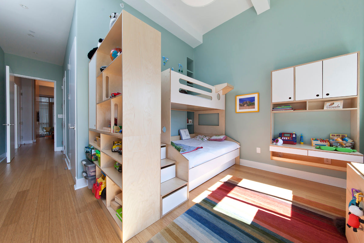 Bright children’s room with bunk bed, cabinets, toys, and colorful rug.