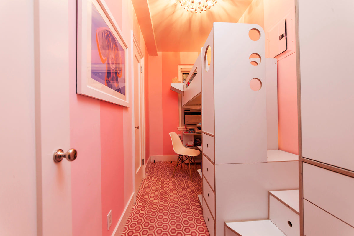 Vibrant pink hallway with patterned carpet and white storage units leading to a desk area.