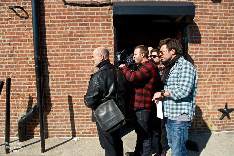 Three individuals stand outside a brick structure.