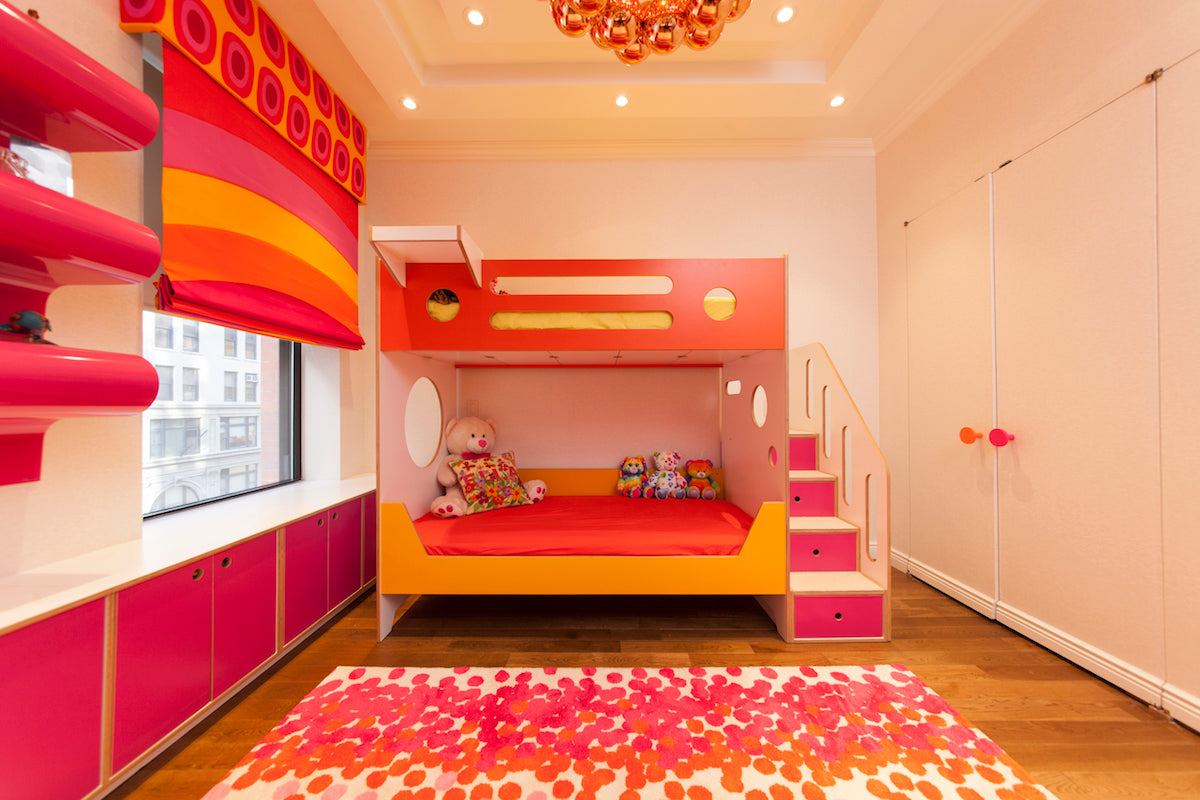 Kids’ room with red bunk bed, pink shelves, floral rug.