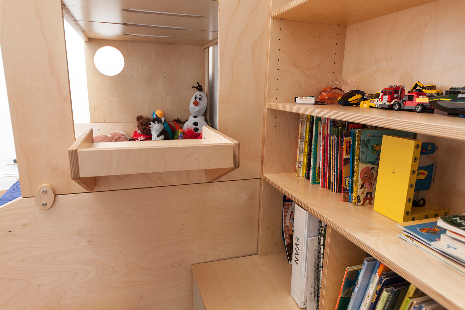 Organized wooden shelves with children’s books and toys.