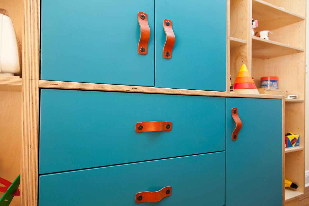 Blue cabinet with orange handles among toys in a room.