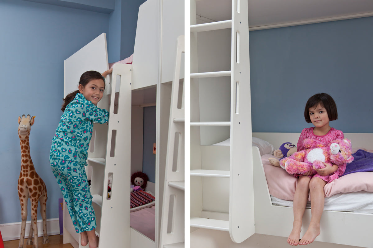 Two children in a blue room with bunk beds, toys, and a giraffe figure.