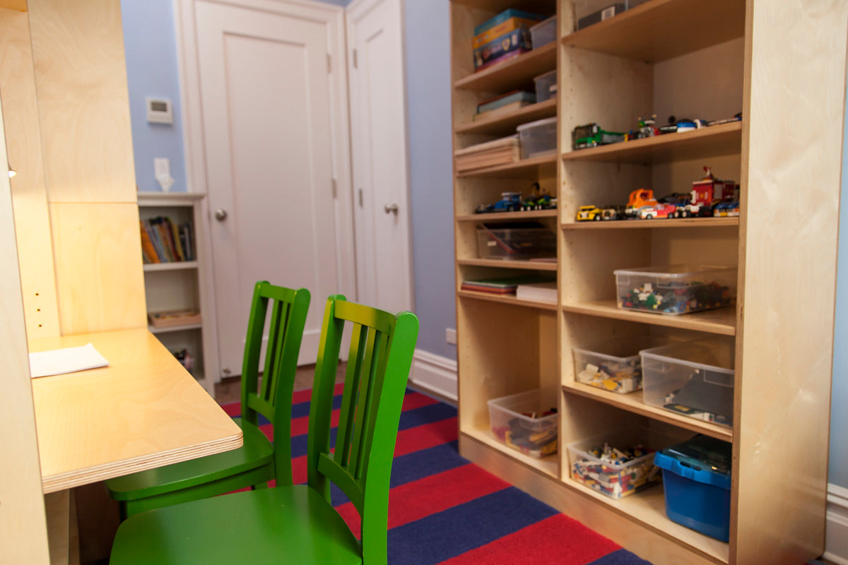 Playroom with table, chairs, and shelves of toys and books.