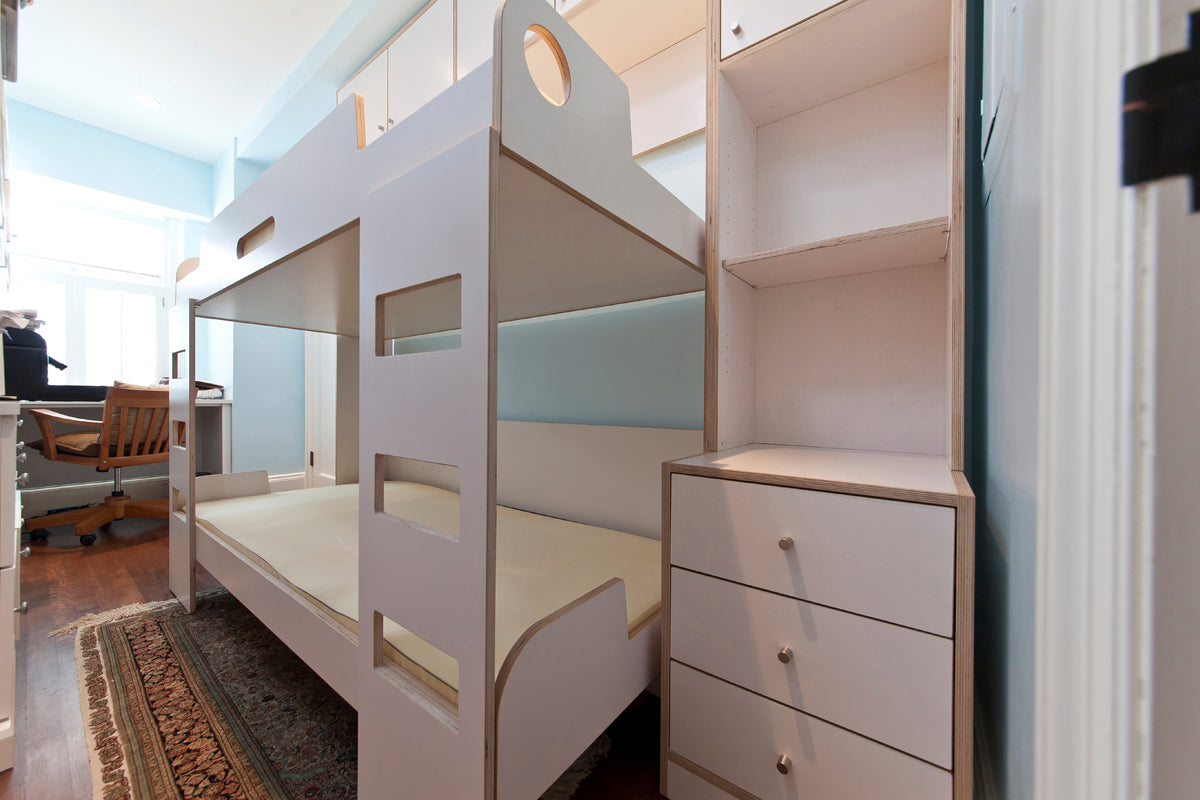 White bunk bed with desk, drawers, and room decor.
