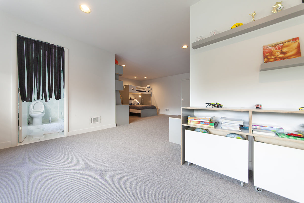 Modern room with bed, shelves, books, and en-suite bathroom.