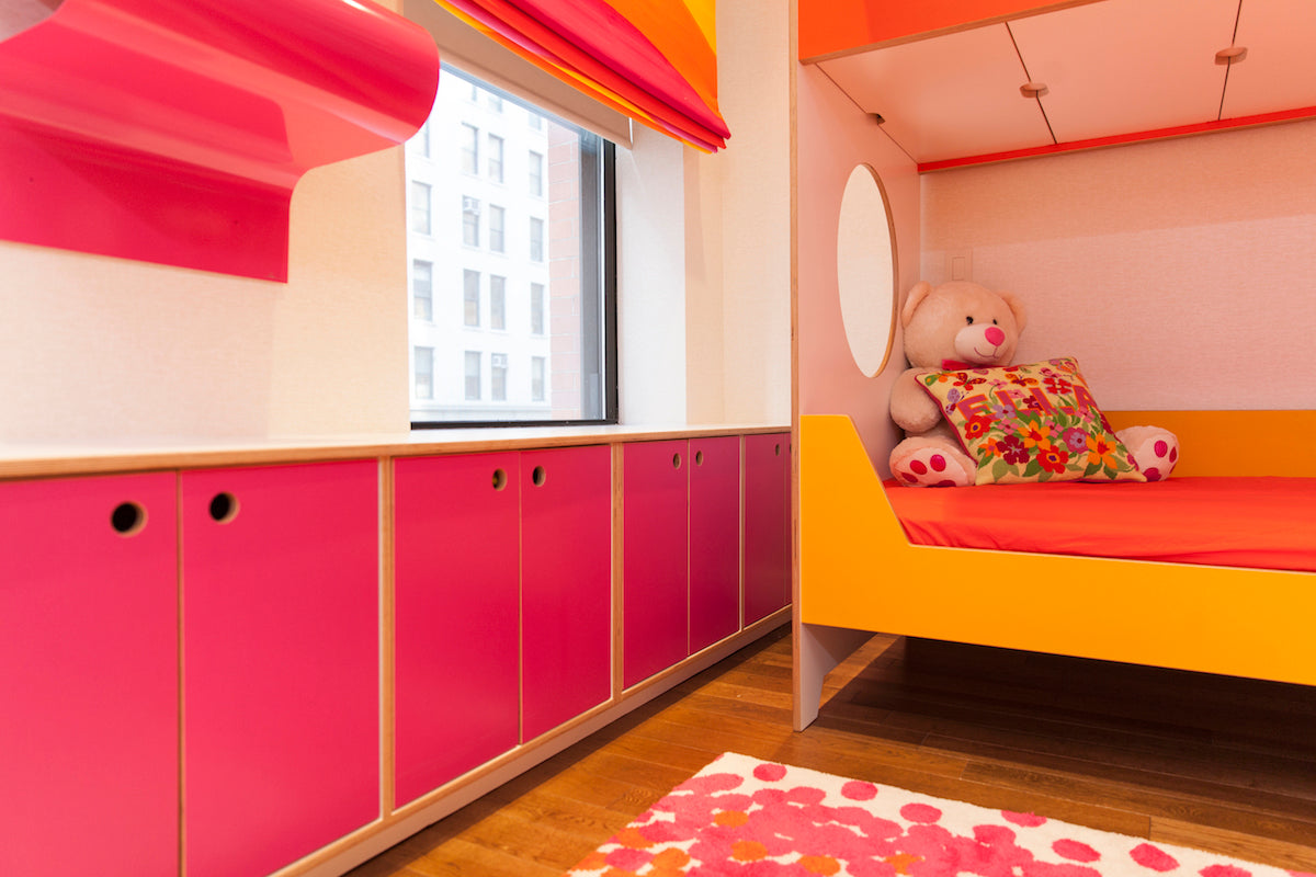 Child’s room with pink cabinets, orange bed, teddy bear.