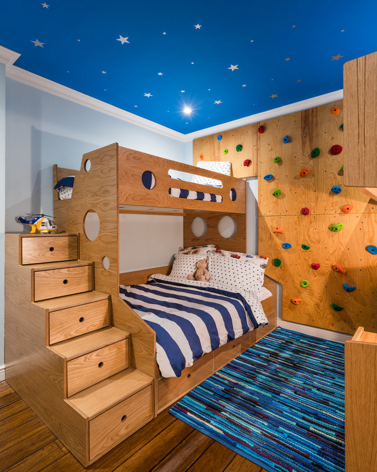 Playful kid’s room with bunk bed, climbing wall, and starry ceiling.