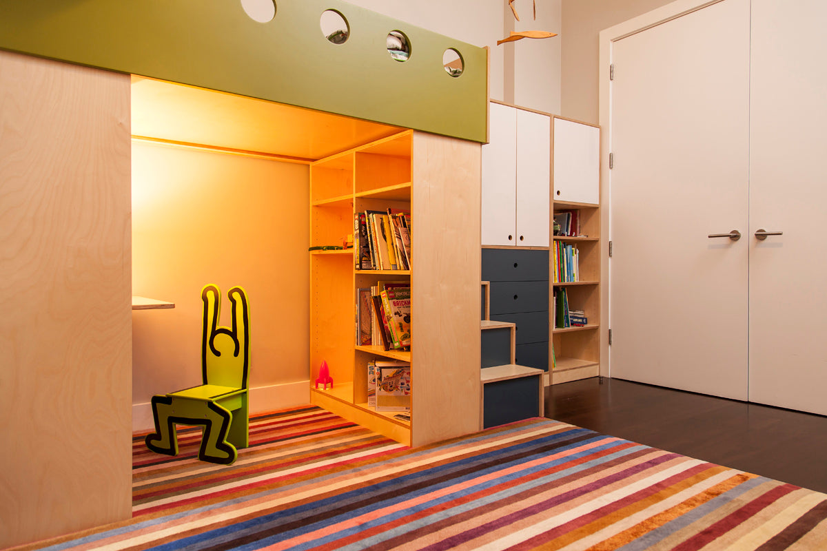 Cozy children’s nook with striped rug, yellow light, whimsical chair.