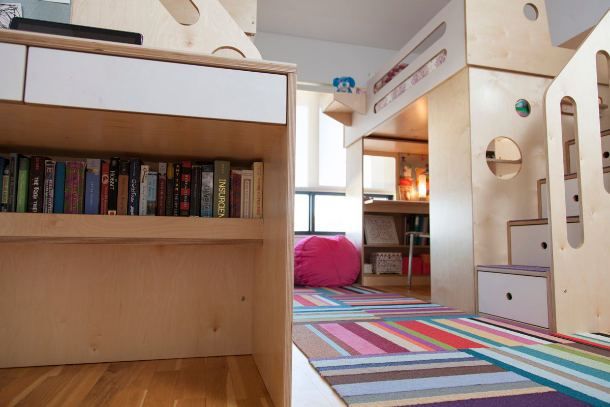 Children’s room with bunk bed, bookshelf, striped rug, and pink beanbag.