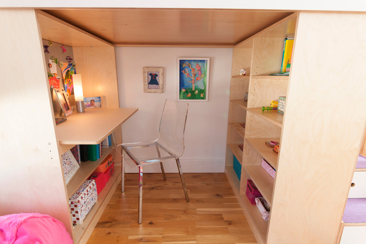 Cozy study area with desk, chair, shelves, art, and vibrant decor.