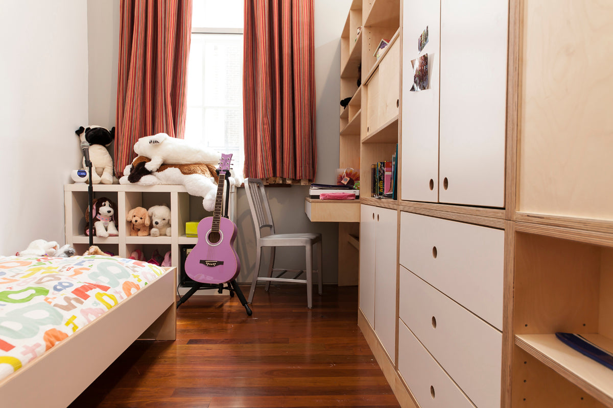 Child’s bedroom with bed, toys, guitar, desk, and shelves.