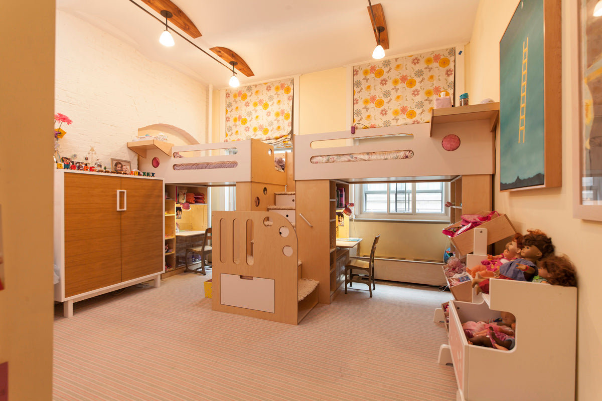 Warmly lit child's bedroom with bunk beds, decorated walls, and a cozy study corner by the window.