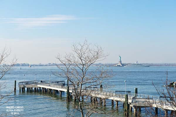 Tree shadow on wall, Gay St & Greenwich Ln signs, distant Statue of Liberty.