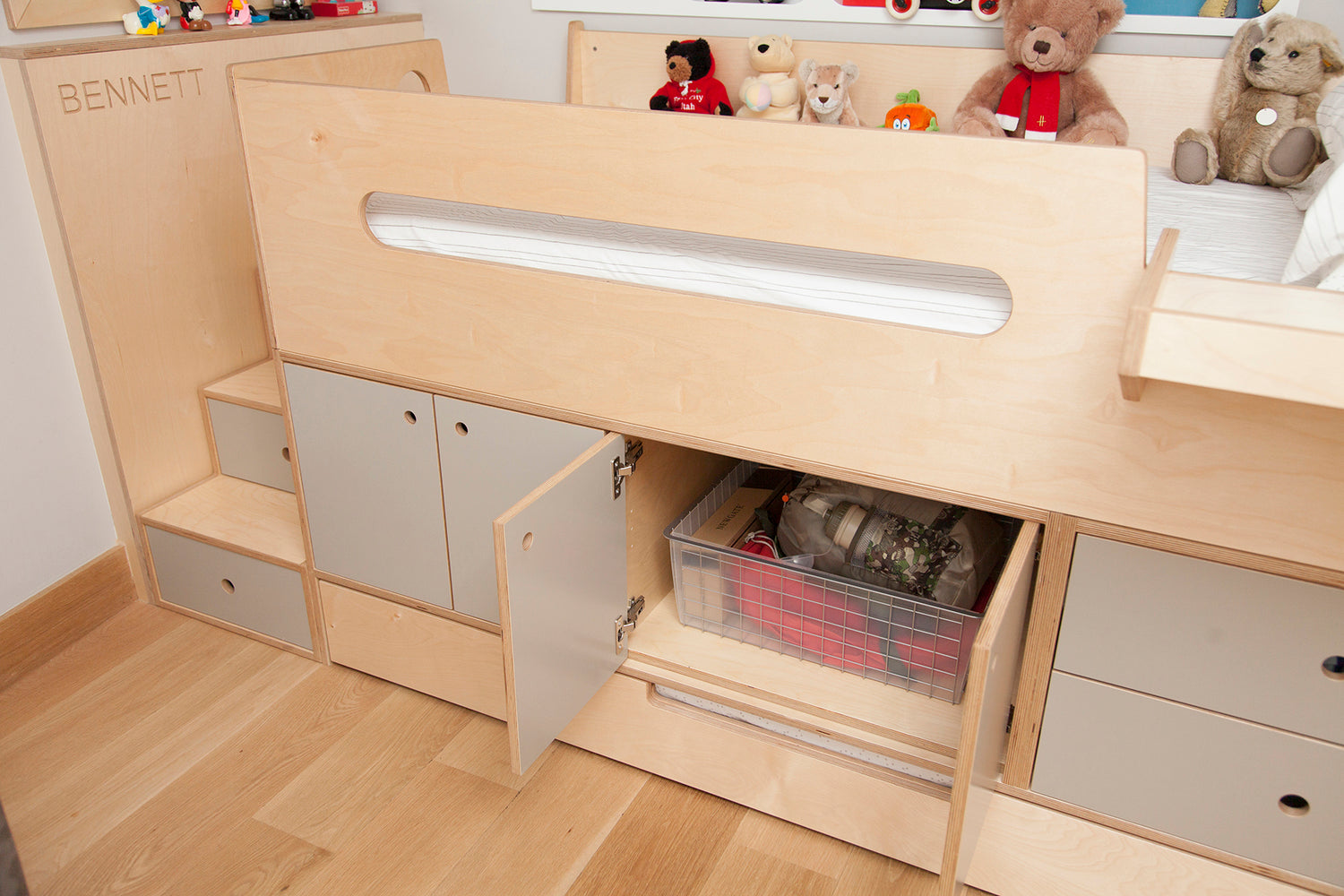 Child’s bed with storage, toys, and an open drawer showing contents.