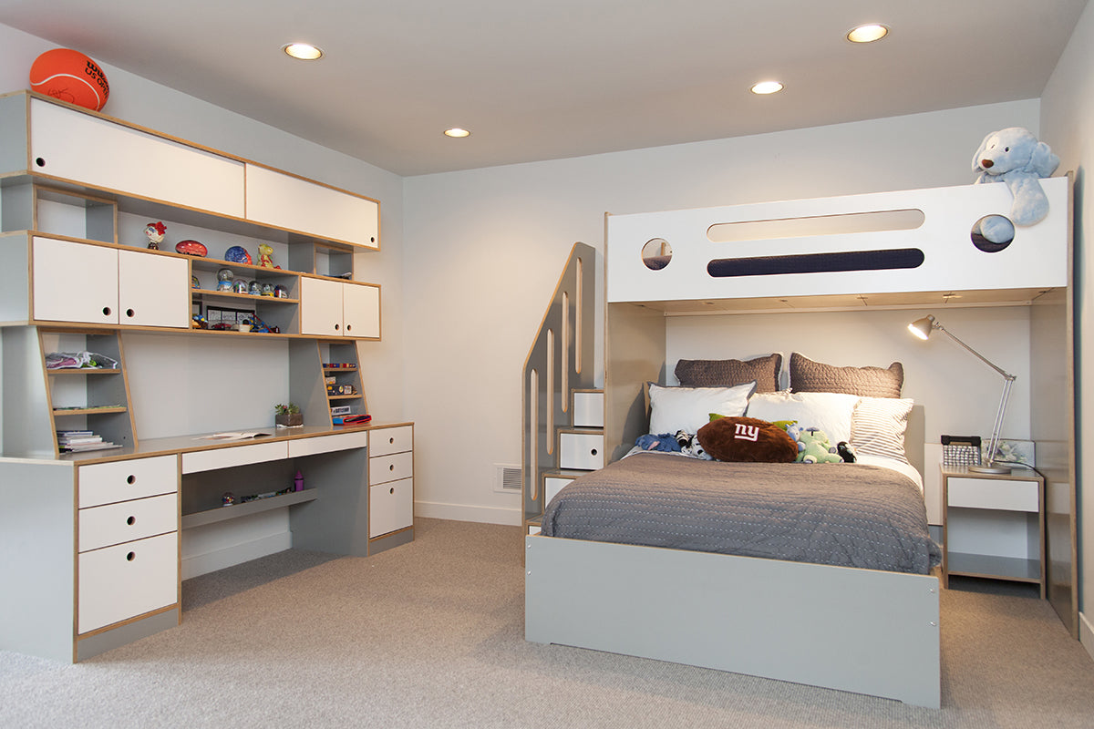 Modern children’s bedroom with bunk bed, desk, and storage.