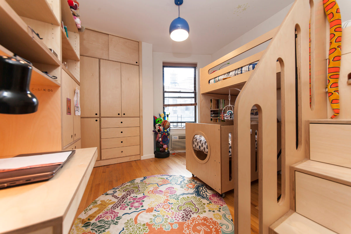 Colorful child's room with a bunk bed, vibrant rug, and ample wooden storage cabinets.