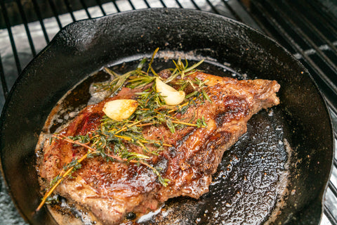 New York Strip in cast iron skillet with butter, garlic, rosemary, and thyme