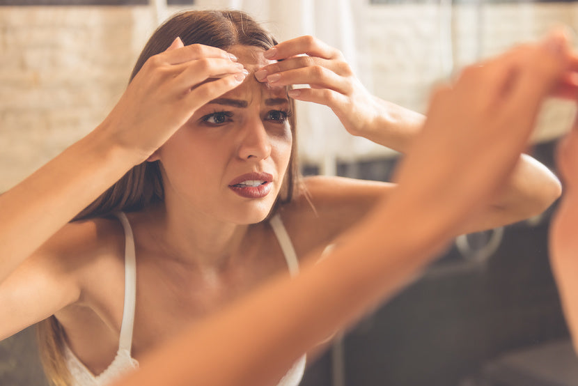 A woman stressing about getting acne breakouts on her forehead