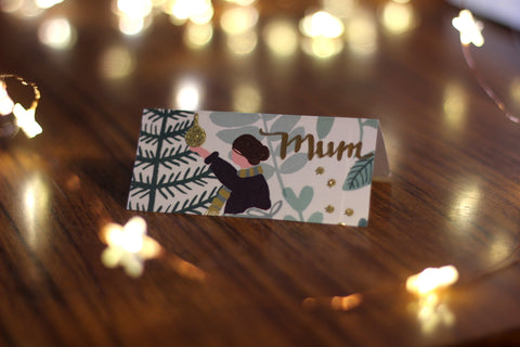 A placecard made from part of old gift wrapping surrounded by fairy lights