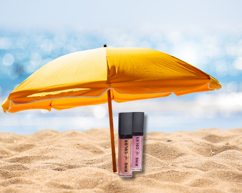 peach and pink glittery lip gloss on sand at beach