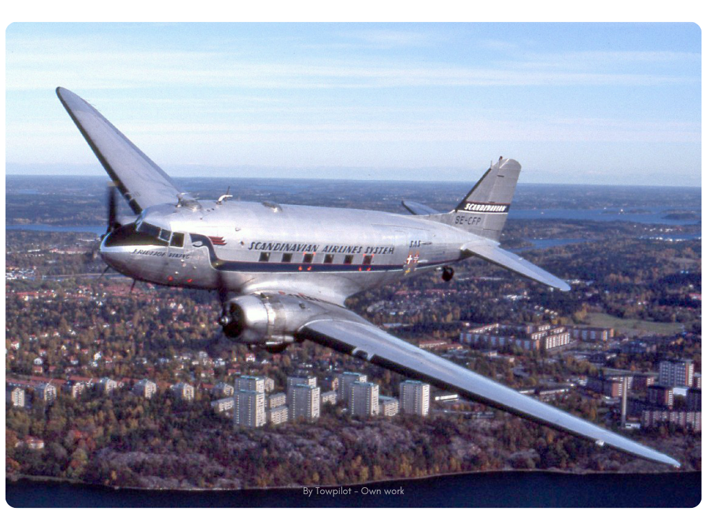 A DC-3 o flying over the city By Towpilot - Own work