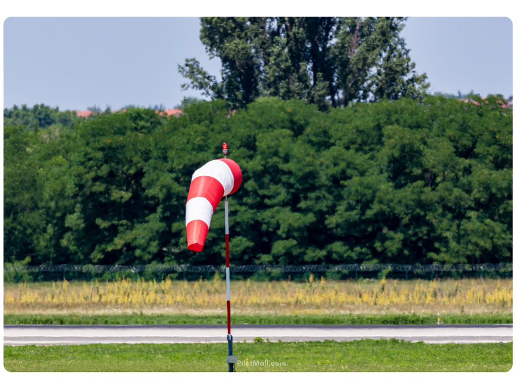 Una manga de viento roja y blanca al costado de una pista - Pilot Mall