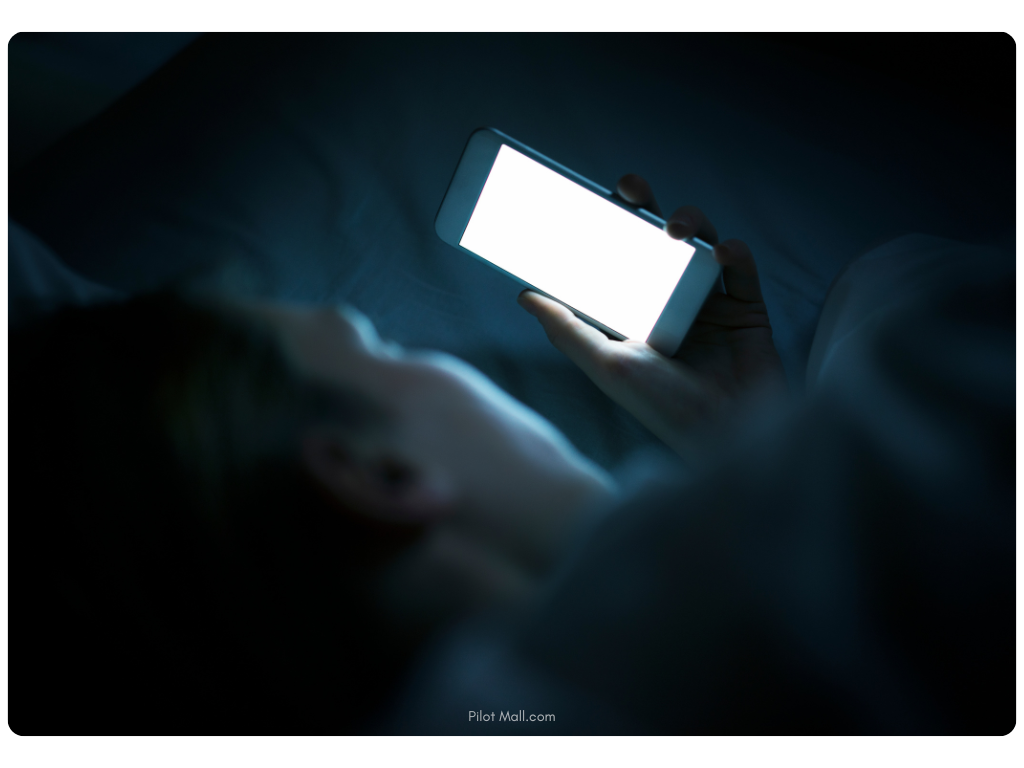 Man in bed in the dark using smartphone - pilot mall