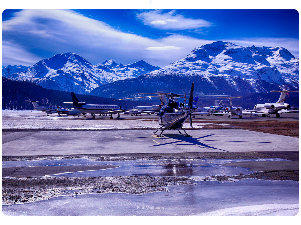 Paisaje de montaña con un helicóptero y varios aviones pequeños estacionados en una pista