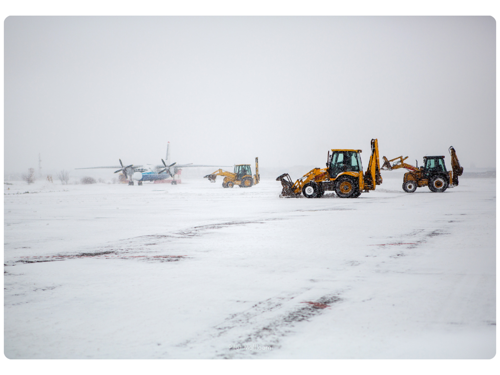 Plows clearing snow off the runway during winter weather - Pilot Mall