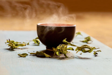 Steaming mug of tea with loose leaf tea