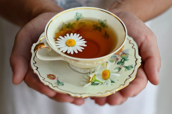 Tea in hands with flowers