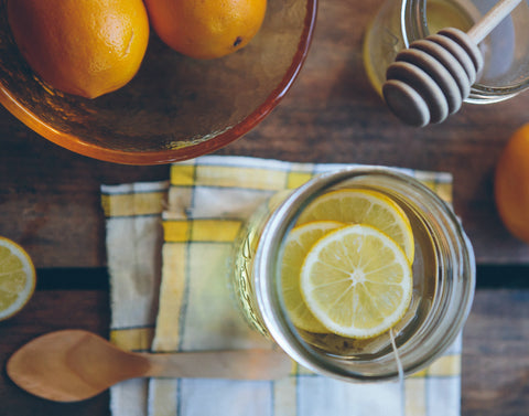 Lemon in a glass with bowl of citrus