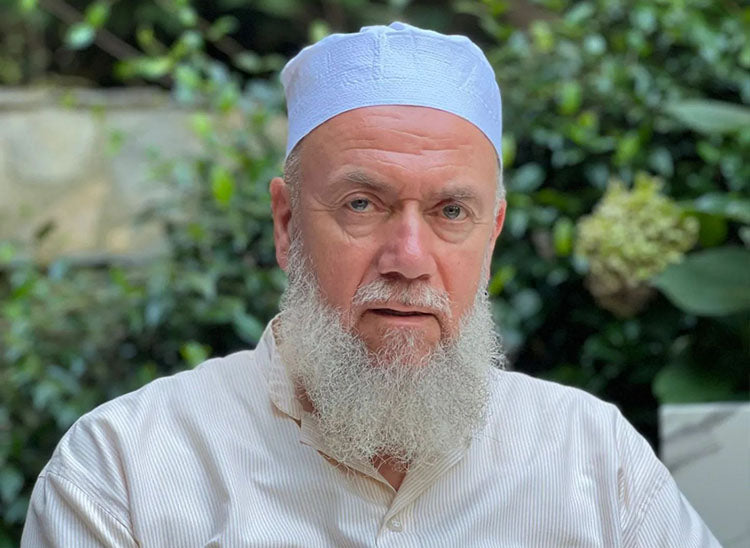 Shaykh Mehmet Adil donning a white pleated top kufi hat.
