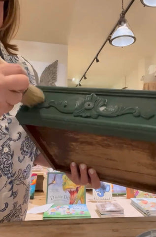 A person from The Owl Box painting a side table drawer.