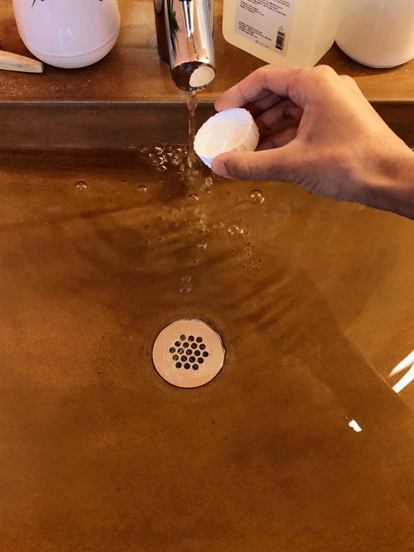 Pouring liquid detergent from a bottle cap into the sink