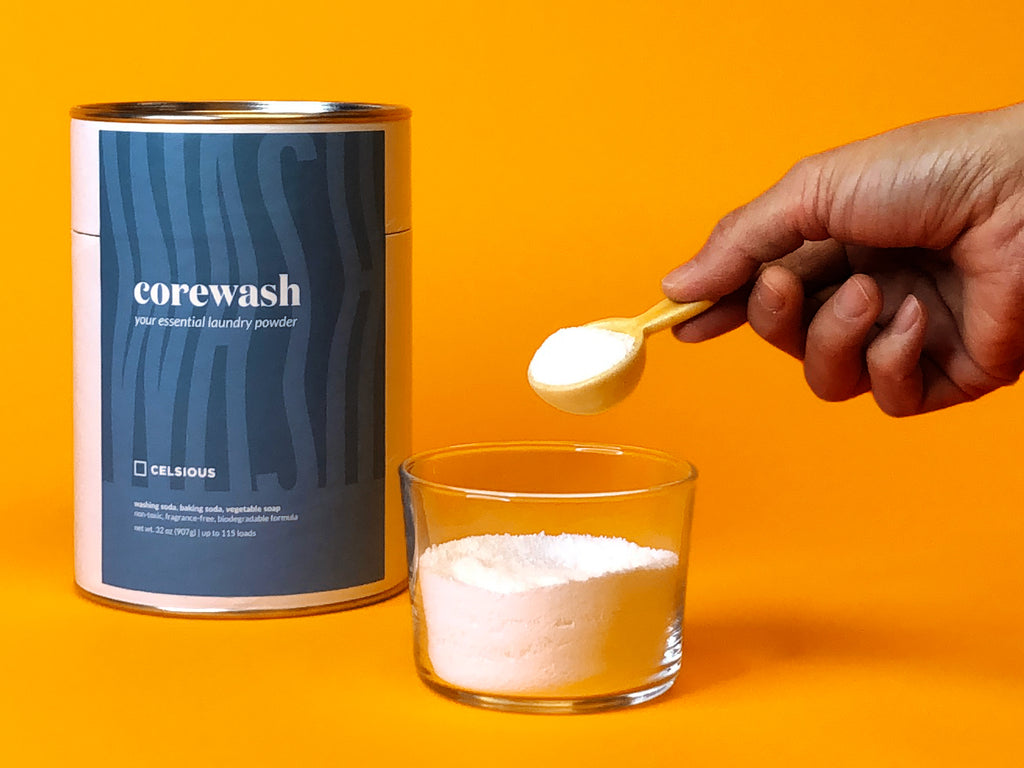 Hand scooping out Corewash laundry powder with mini ceramic scoop