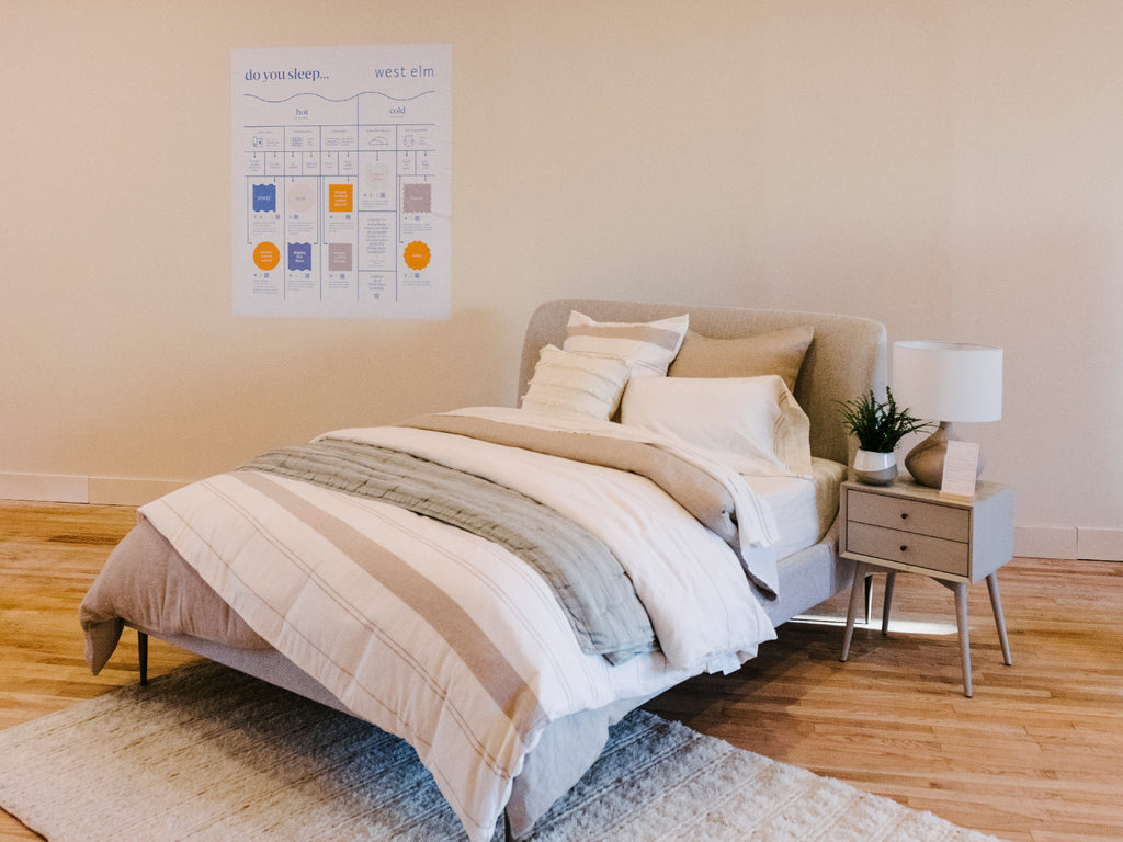 A comfy looking bed put together by West Elm, featuring cream colored bedding and natural materials