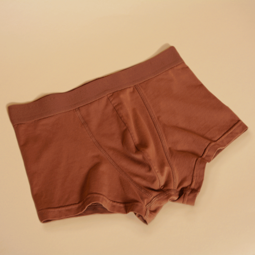 A gif of terracotta colored boxer briefs folding into a neat rectangle