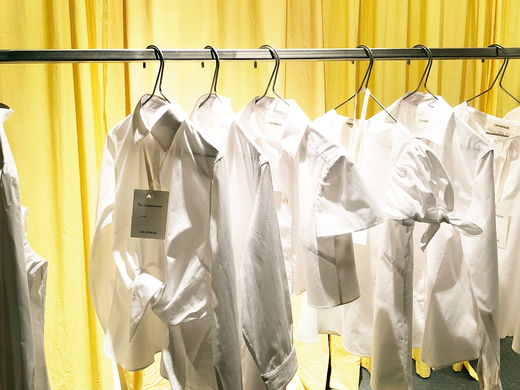 Crisp white blouses hang from a clothes rack