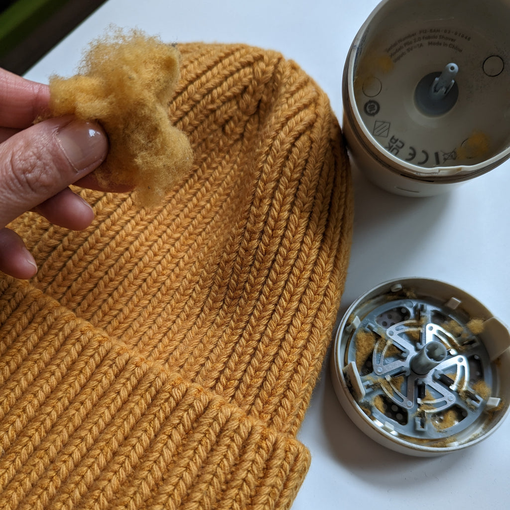 A hand holds a ball of fuzz taken from the inside of a fabric shaver